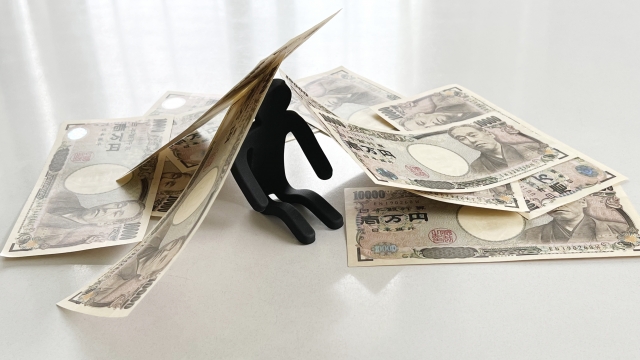 お金の上でうなだれる。奥州市で借金返済の相談は無料でできます